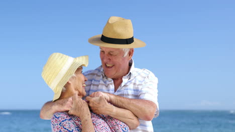una pareja de mayores abrazándose en la playa.