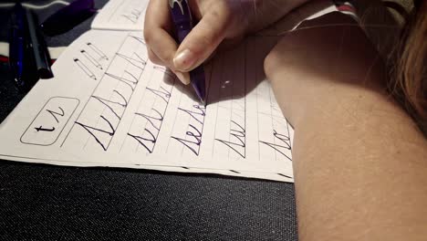 niño sentado en la mesa practicando se unió a escribir la repetición de la tarea en un cuaderno rayado