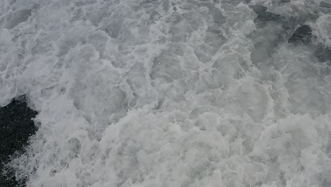 top-down perspective of foamy waves splashing onto a philippine coastal beach at looc bay