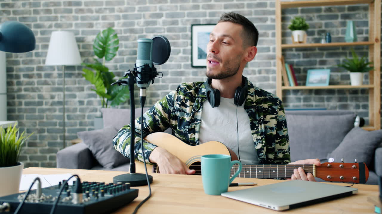 Uomo che canta e suona la chitarra acustica in uno studio di registrazione casalingo