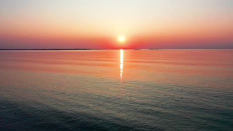 Vista-Aérea-Por-Drones-De-La-Colorida-Puesta-De-Sol-En-La-Playa-En-Saco,-Maine,-Con-Colores-Brillantes-Que-Se-Reflejan-En-Las-Tranquilas-Olas-Del-Océano-A-Lo-Largo-De-La-Costa-Atlántica-De-Nueva-Inglaterra