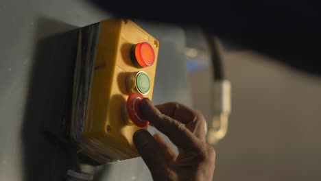 técnico de servicio que opera un interruptor de parada de emergencia de una máquina en una fábrica