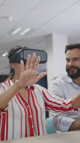 Vertical video of diverse business people talking and using vr headset in office
