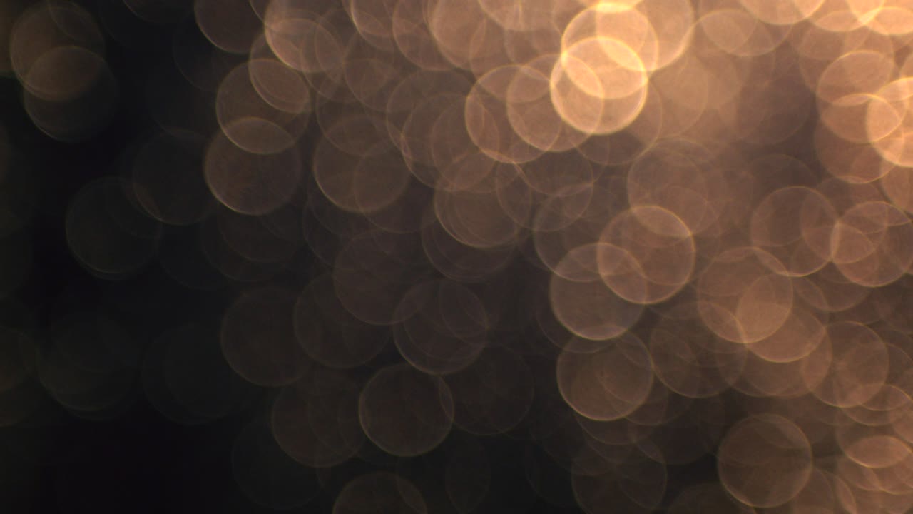 Cerchi bokeh dorati caldi in movimento su sfondo nero