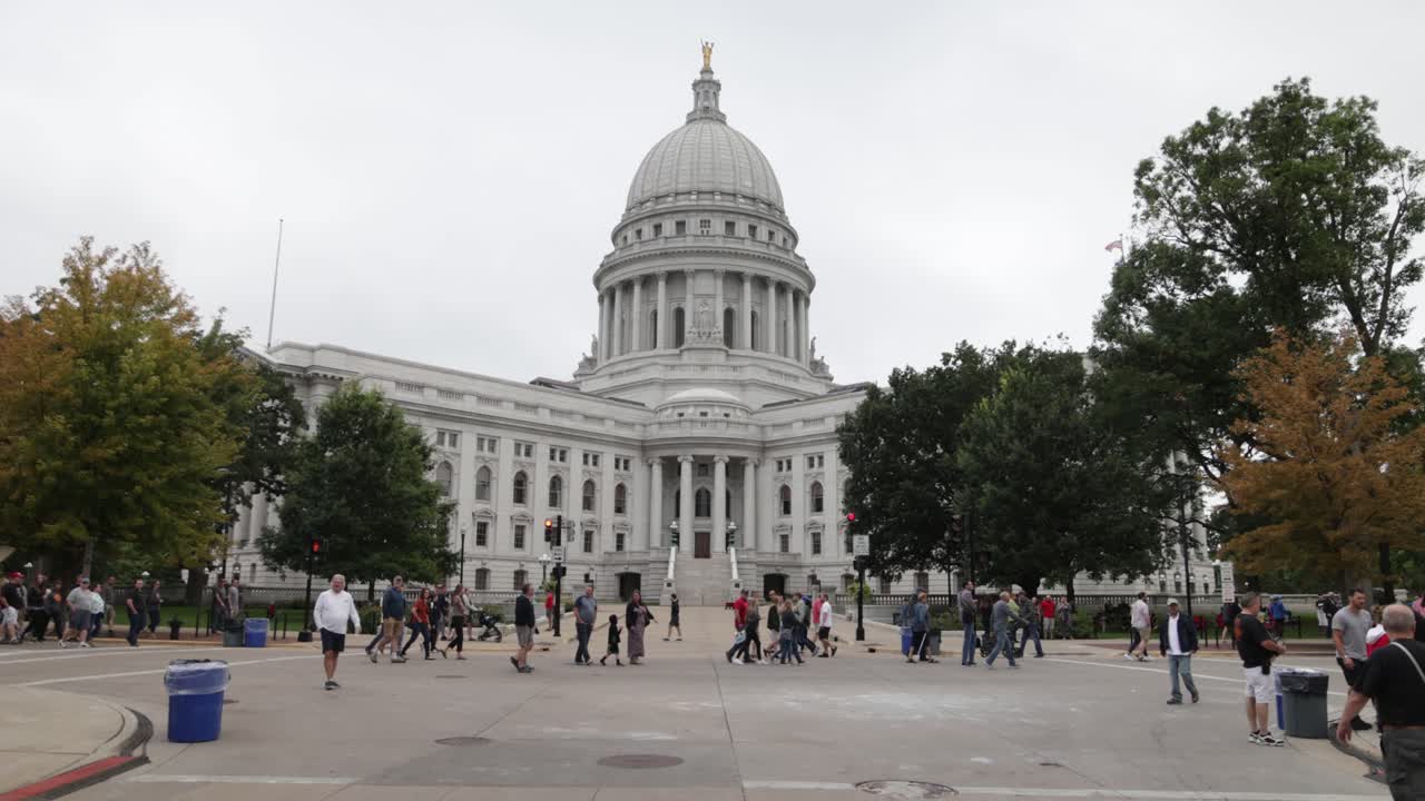 Wisconsin state capitol building in Madison, Wisconsin and group of people on grounds with gimbal video walking forward.