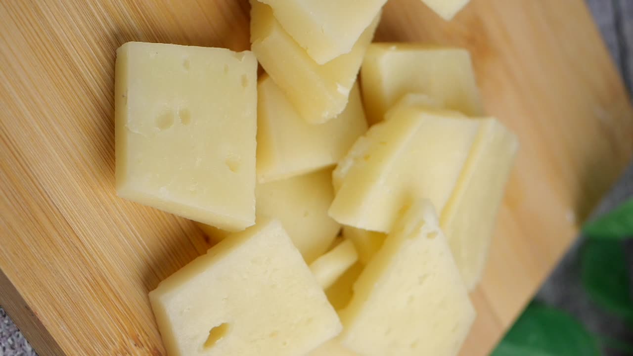 Garfo pegando um cubo de queijo de uma tábua de madeira