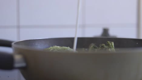 slow motion static shot of a man pouring milk into a bowl of vegetables