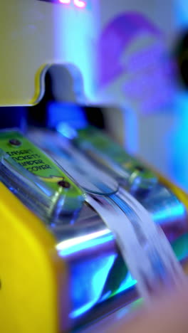 closeup of arcade ticket counting machine with hand inserting paper ticket under cover