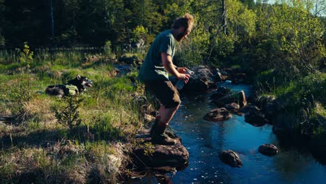 a caucasian man drinking from a pristine flowing river