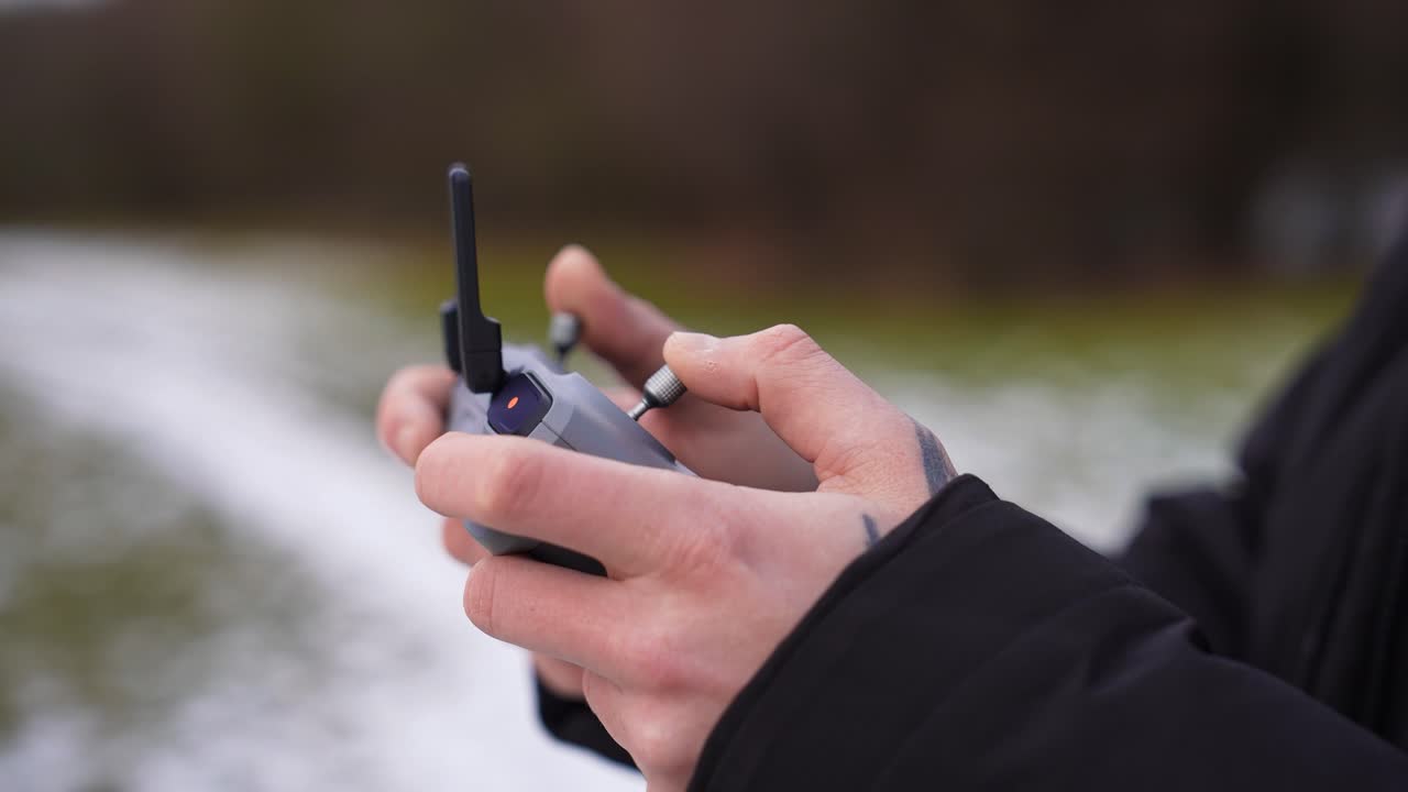 Close-up of hands operating drone remote controller in winter environment