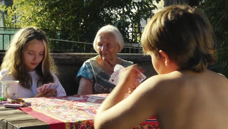 children enjoy playing card game activity with grandma in sunny garden