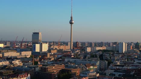 la torre de televisión de berlin de pie alto sobre la torre y el ayuntamiento rojo, bañado en el cálido resplandor de la hora dorada. fantástica vista aérea vuelo panorama órbita drone