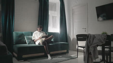 champ sitting on sofa in cozy living room, reading tablet with natural light streaming in from large windows. relaxed atmosphere with modern furniture and soft shadows