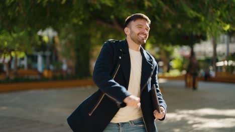 young hispanic man holding laptop dancing at park