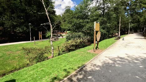 trail in the public park with fitness equipment for people between gardens and the river, benches to sit and relax enjoying nature, sunny summer day, shooting traveling forward, ordes, galicia, spain