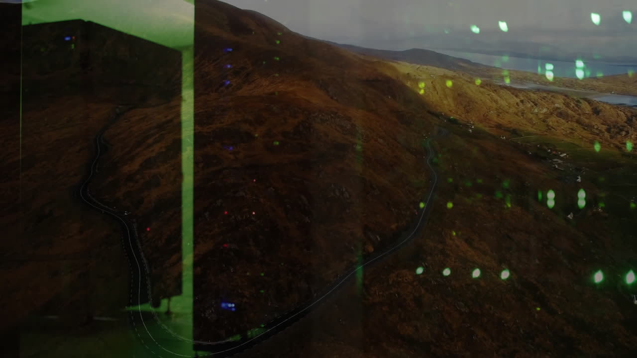 Green digital interface animation over winding road through mountainous landscape