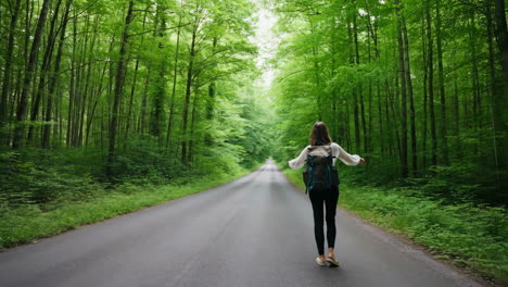 woman walking on a road through a lush green forest