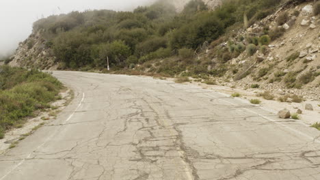 drone flying low over an windy mountain road and slowly following the road