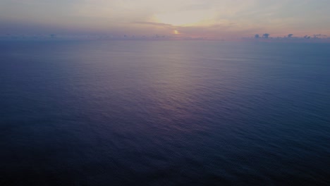 aerial tilting shot from a lighthouse on a cliff edge into the sunset