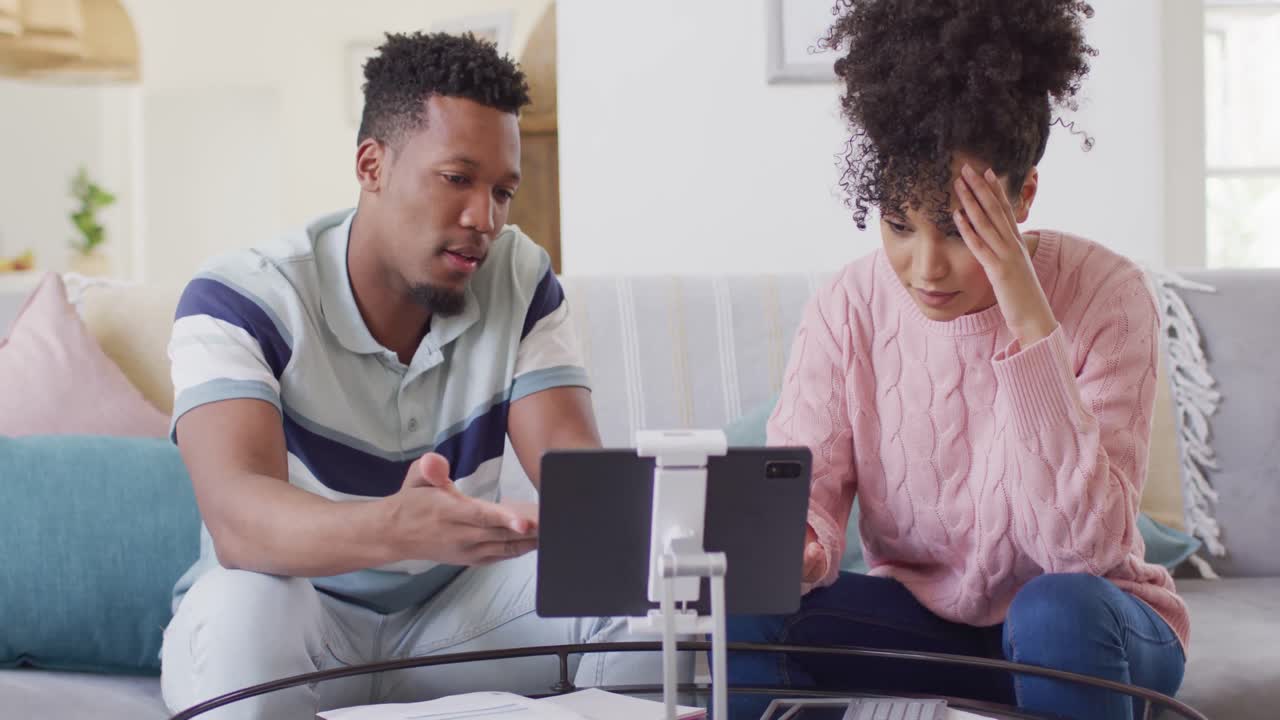 African american couple with documents and tablet in living room