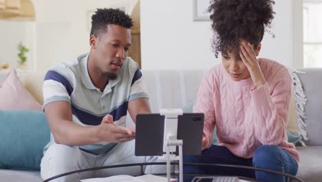 pareja afroamericana con documentos y tableta en la sala de estar
