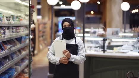 Retrato-De-Una-Trabajadora-Musulmana-De-Supermercado-Parada-Con-Una-Tableta-En-Las-Manos