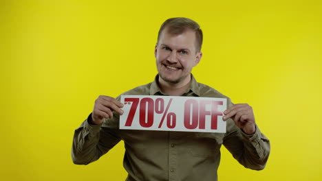 smiling man showing up to 70 percent off inscriptions signs, rejoicing good discounts, low prices