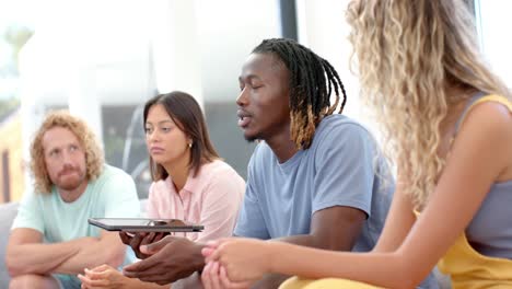 serious diverse friends and male therapist with tablet talking during group therapy, slow motion