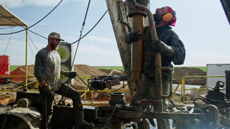 two cheerful bearded men working at the site for drilling oil or gas. workers maintaining the equipment for natural resources production.
