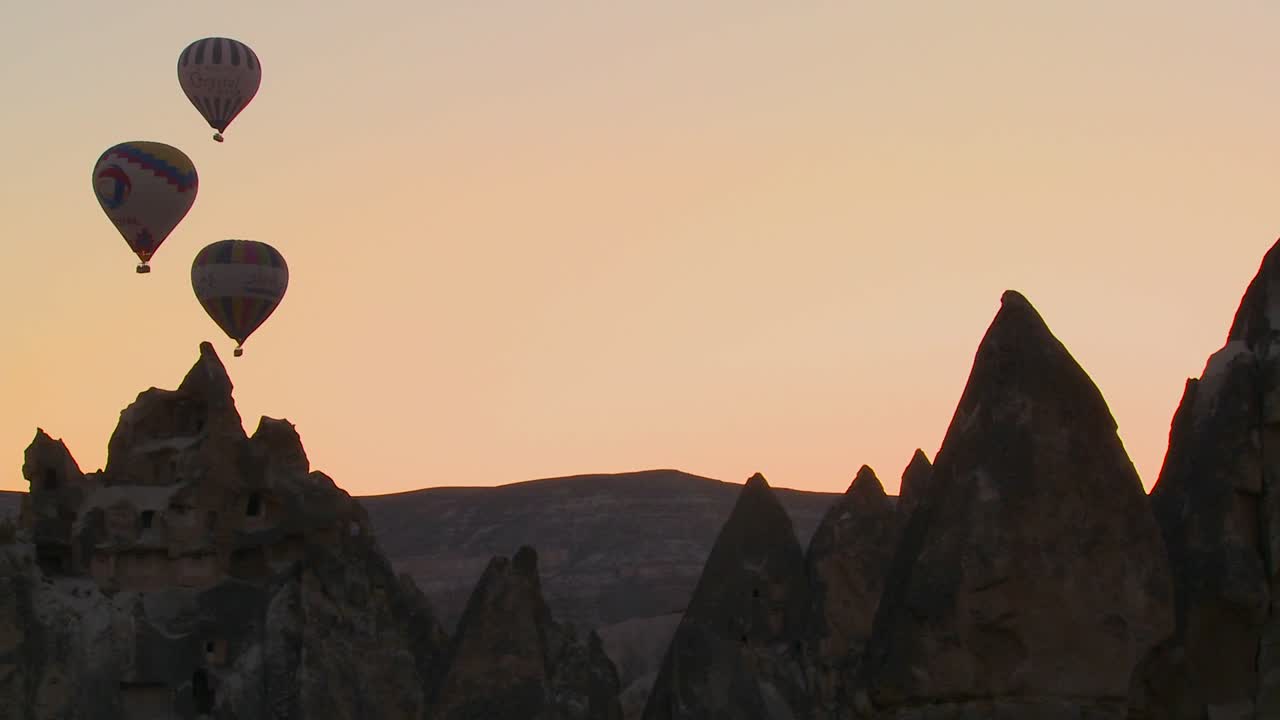 tres globos aerostáticos están bellamente recortados contra un pico de montaña en capadocia turquía