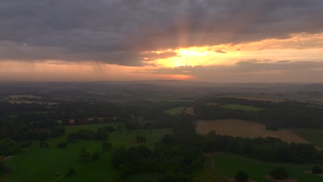 sunrise with rays of light over misty rural south west english countryside. camera reversing. summer. cornwall, uk.
