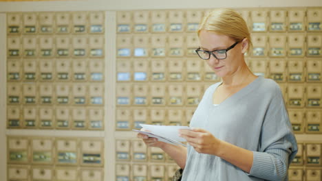 una mujer mira las cartas que acaba de recibir debería estar en la oficina de correos en el fondo del correo