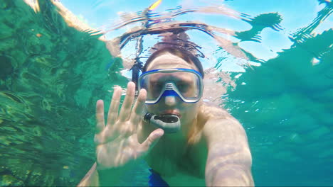 diver makes selfie waving at the camera - underwater