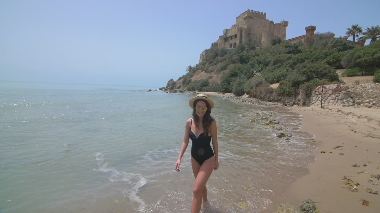 검은 수영복을 입은 여자가 해변에서 고 있다