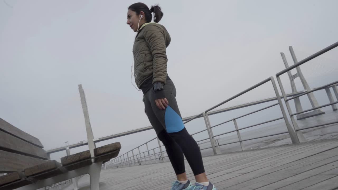 Vista dall'alto di una giovane donna sportiva concentrata che fa squat in riva al mare