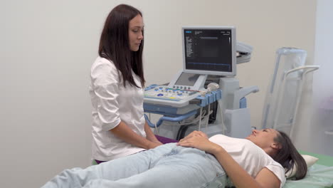 patient lying on hospital gurney, female doctor does ultrasound