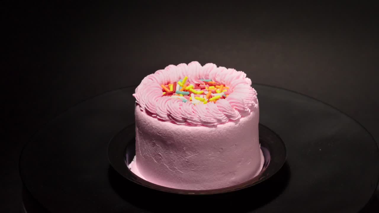 mini personal petite individual slice Strawberry berries jelly cake withe cream in a turn table with black background loop tasty treat sweet delicious sprinkles colourful pink
