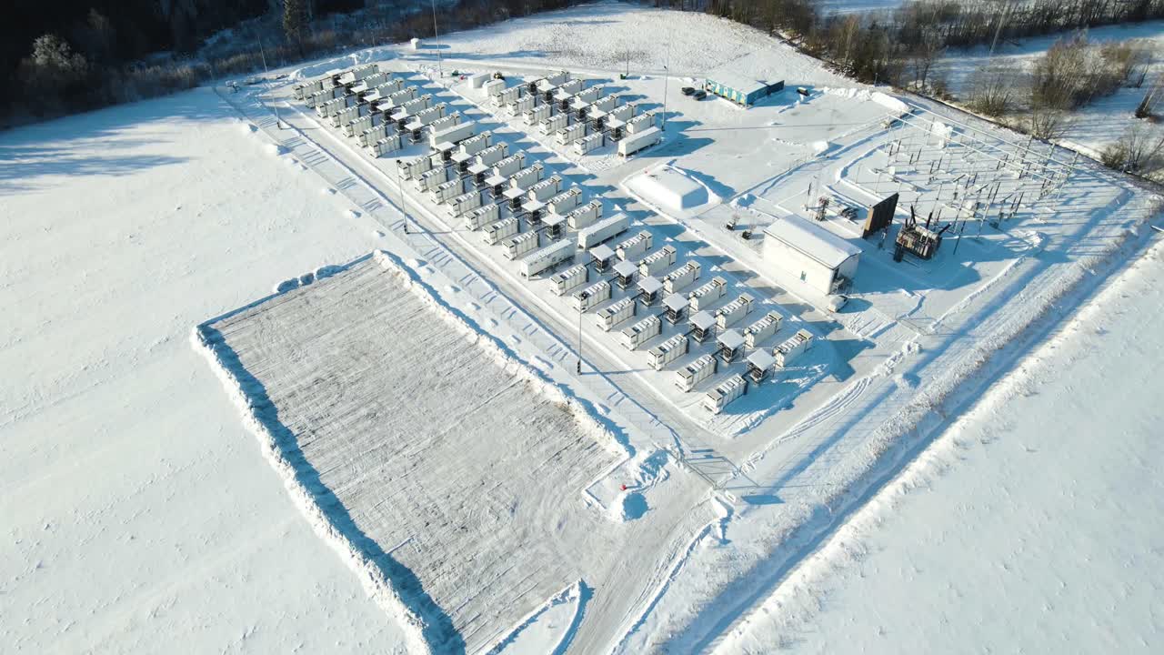 Široký letecký záběr ukazuje plně zasněžený bateriový park a podpůrnou elektrickou rozvodnu, zajišťující spolehlivé dodávky energie z obnovitelných zdrojů.