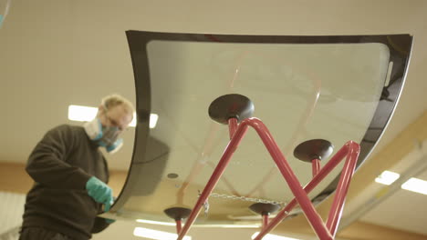 Low-angle-upwards-view-of-technician-applying-primer-to-replacement-windshield