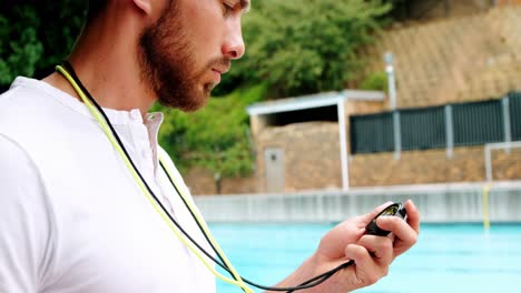 entrenador de natación mirando el reloj de parada cerca de la piscina