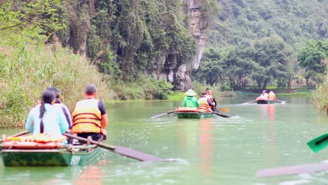 people rowing boats through scenic river landscape