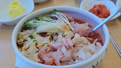 bowl of delicious mulhoe served with various sashimi in a korean restaurant