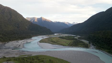 Braided-river-coming-from-rugged-mountains-during-golden-hour,-aerial-establishing-shot