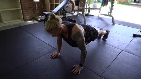 tattoo man muscles in home gym doing push ups workout