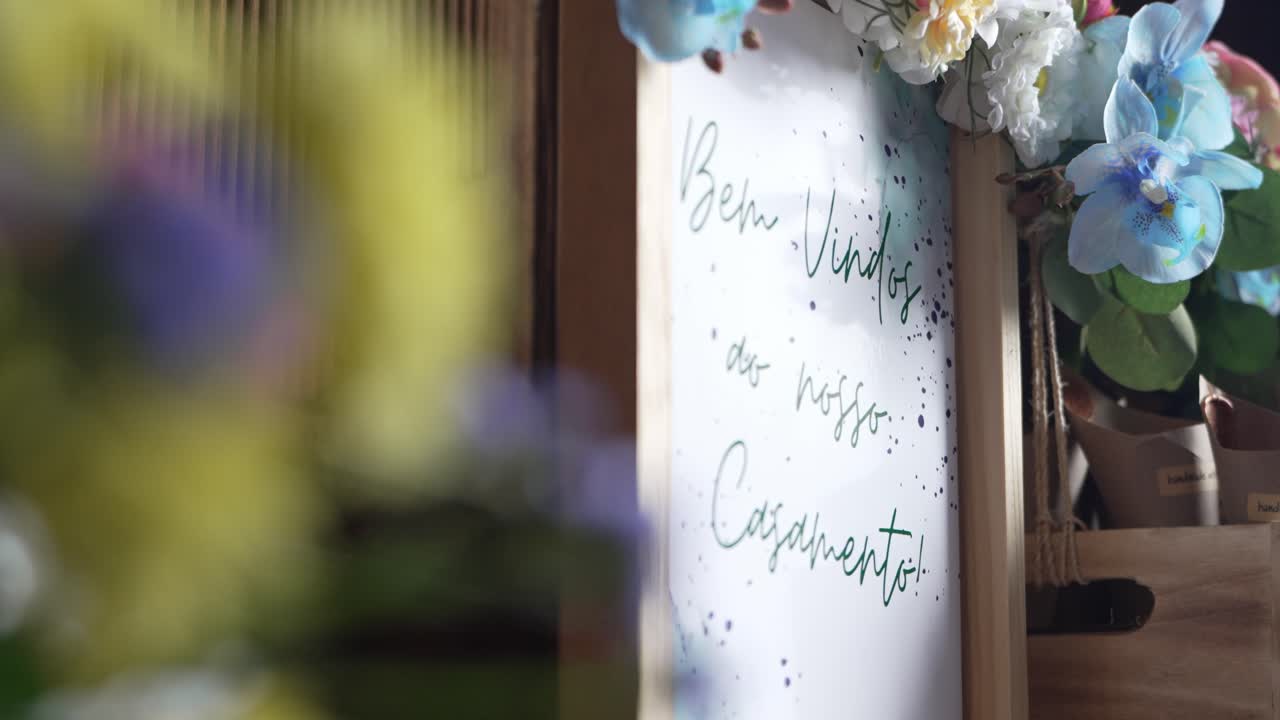 Artistic wedding welcome sign reading "Bem-Vindos ao nosso Casamento" adorned with flowers