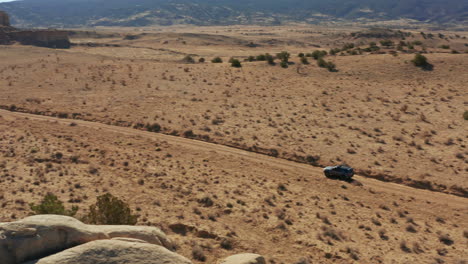 panning with car driving down rural dirt road through desert landscape