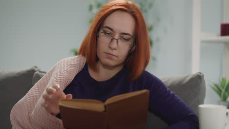 concentrated housewife in glasses reads book flipping pages