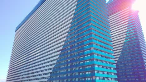 shot of reflections of sun, clouds and sky on glass windows of city skyscraper.