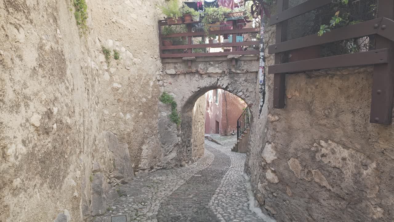 Historical Empty medieval cobble street with stone archway Malcesine