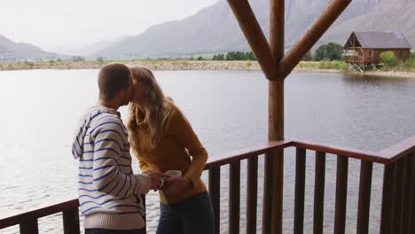 caucasian couple spending time at home together, kissing outside the cabin